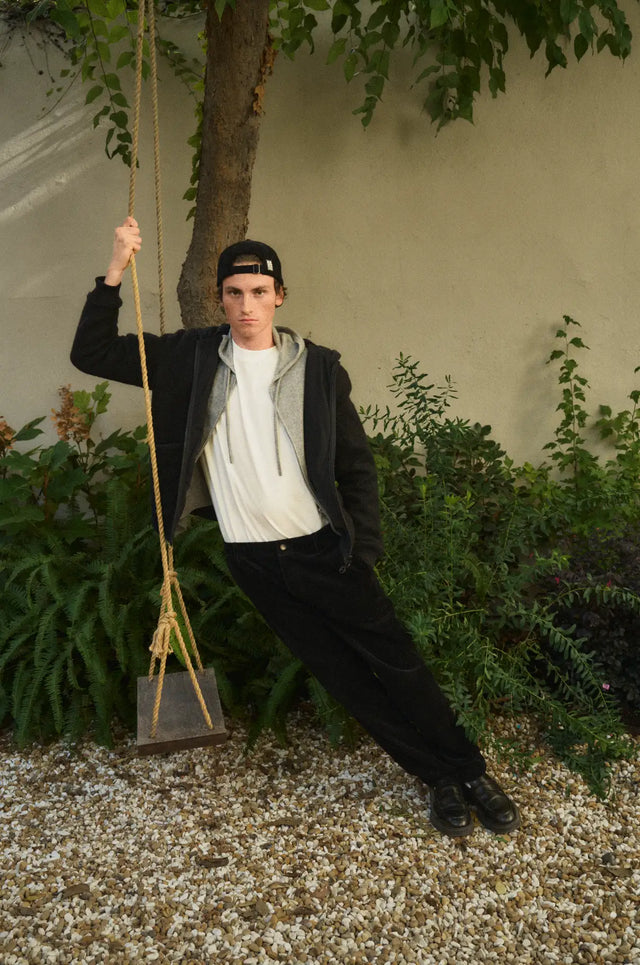 Sweat à capuche noir et blanc avec capuche, pantalon sombre, casquette de baseball.