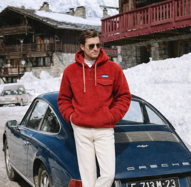 Sweat à capuche en polaire rouge avec des cordons beige et un petit logo bleu sur la poitrine.