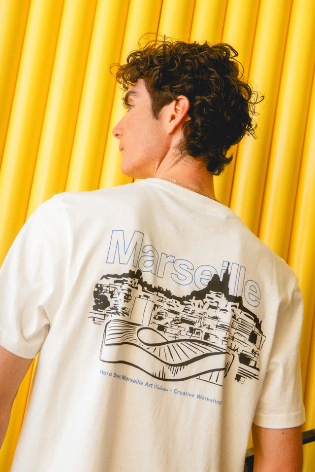T-shirt blanc avec impression graphique noire et bleue du skyline de Marseille et du texte.